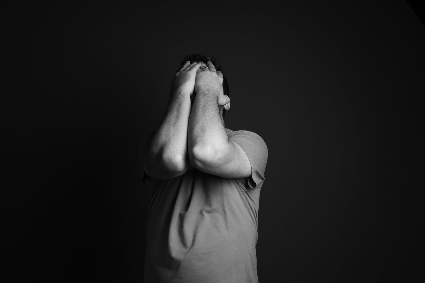 A person sitting with both hands covering their face