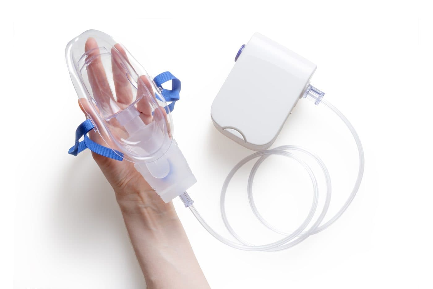 A hand holding a nebulizer mask beside its compressor