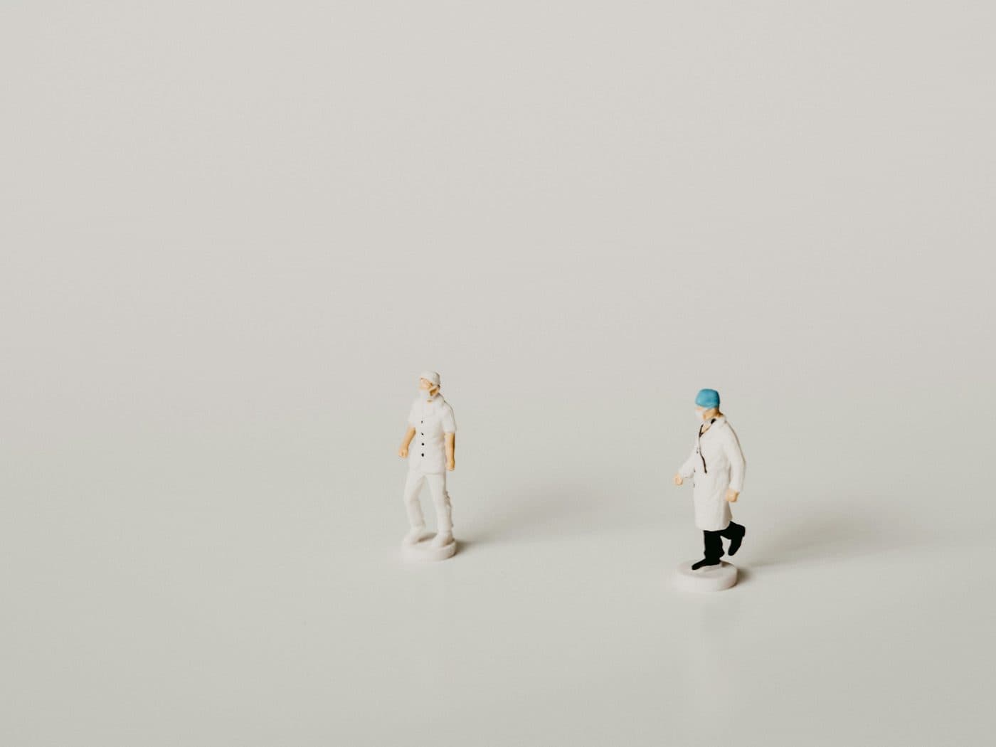 Two miniature figures of medical staff on a plain background