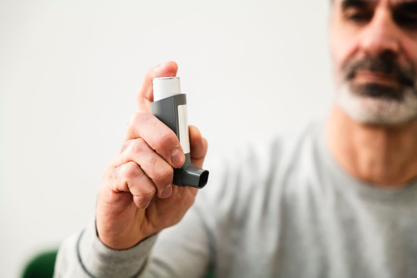 A man holding a metered dose inhaler used to manage COPD symptoms