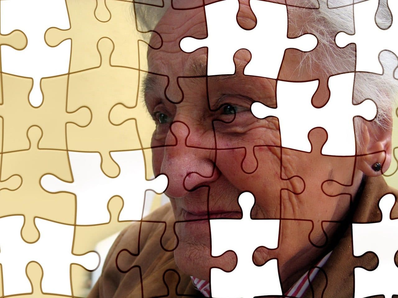 An older adult pictured behind missing jigsaw puzzle pieces, illustrating memory loss