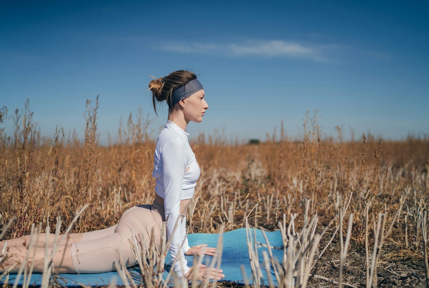 A woman stretching on a yoga mat in an open field