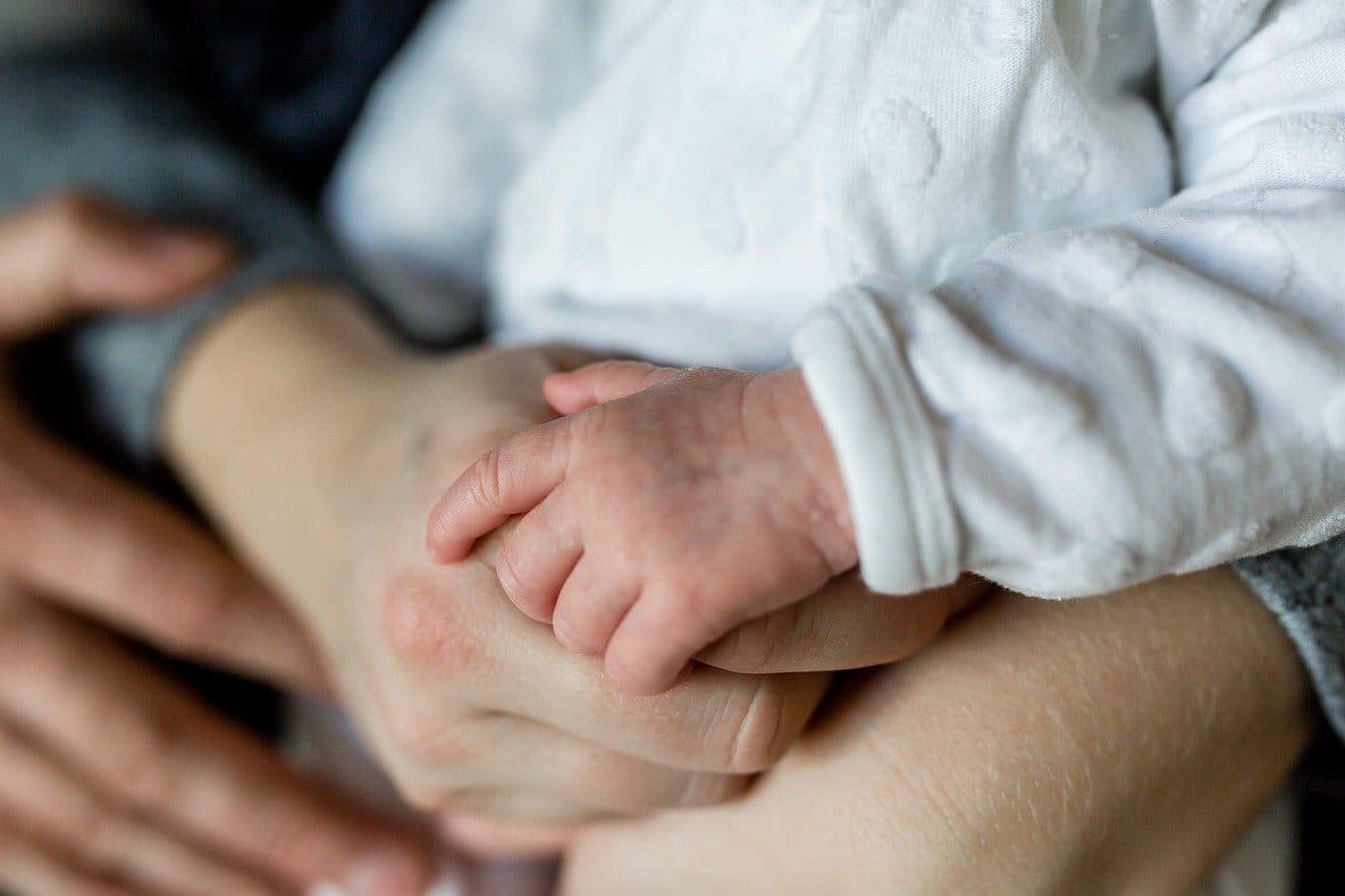 A newborn hand resting in an adult hand