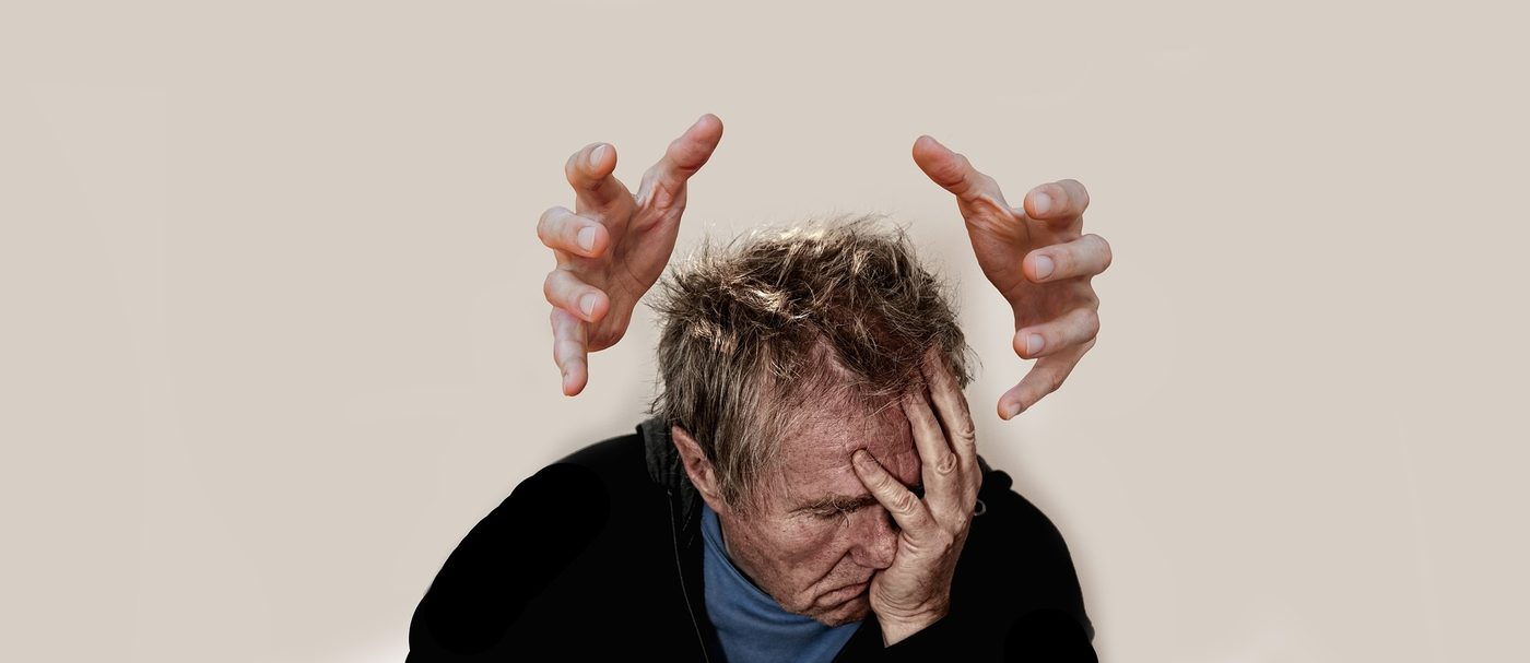 A person holding their head with a pained expression during a severe headache.