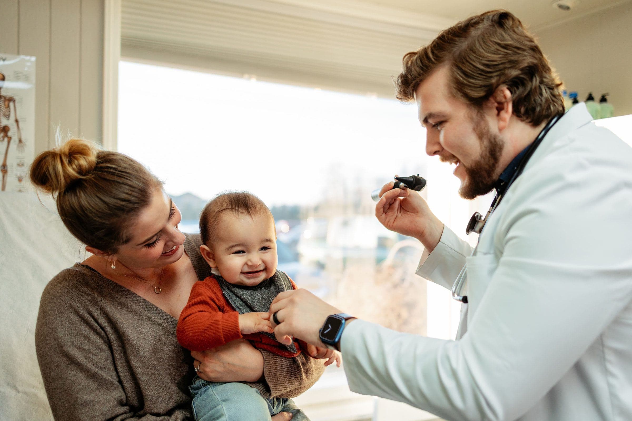A provider at Guardian Primary Care smiling with a mother and her baby during an office visit